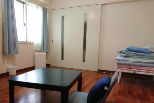 een woonkamer met een tafel en een deur bij Guesthouse Seaglass in Itoman
