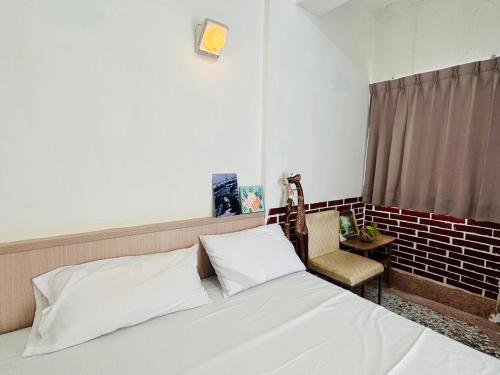 a bedroom with a white bed and a chair at Shi Bi Hotel in Gukeng