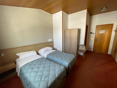 ein Hotelzimmer mit 2 Betten und einem Stuhl in der Unterkunft Hotel Tarvis in Tarvis