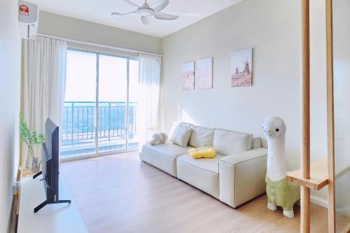 uma sala de estar com um sofá branco e uma televisão em Home Cinema - BM City Centre - 4km to Icon City at The Metropol Muji Style Apartment em Bukit Mertajam