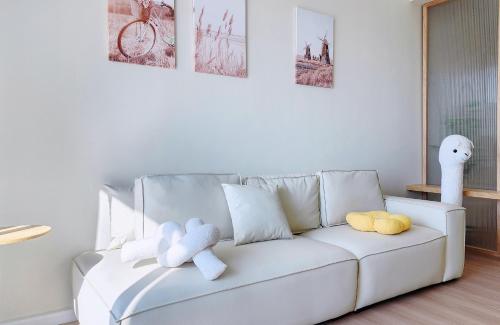 a white couch with stuffed animals on it in a living room at Home Cinema - BM City Centre - 4km to Icon City at The Metropol Muji Style Apartment in Bukit Mertajam