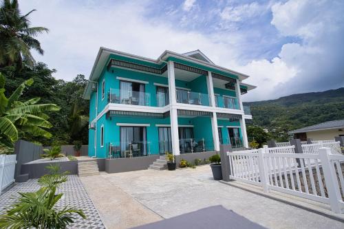 a blue house with a white fence in front of it at Sunset Haven Villa in Beau Vallon