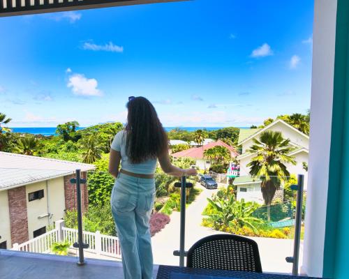 a woman standing on a balcony looking out at the ocean at Sunset Haven Villa in Beau Vallon