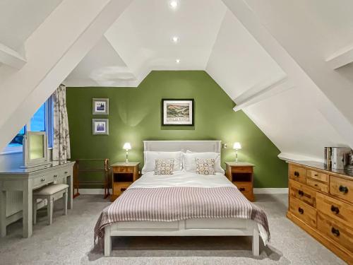 1 dormitorio con cama blanca y pared verde en 8 Old School Mews, en Shanklin