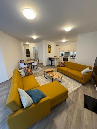 a living room with a yellow couch and a kitchen at to be apartments Deluxe-Suites in Weiden