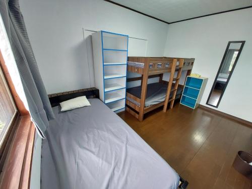 ein Schlafzimmer mit einem Bett und ein Zimmer mit einem Etagenbett in der Unterkunft Finecamp Guesthouse Share Room 相部屋 in Miyazaki