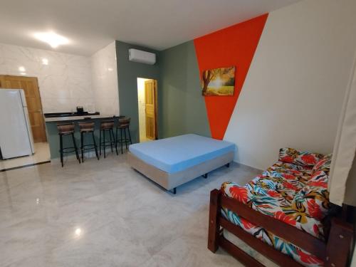 a room with a bed and a kitchen with stools at Apartamentos Kairos in Ubatuba