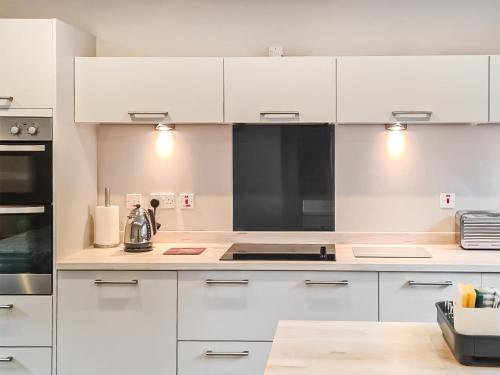 a white kitchen with white cabinets and appliances at The Shore in Fortrose