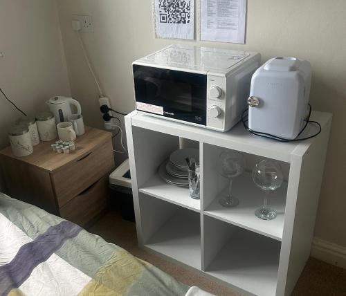 a white cabinet with a microwave and a blender on it at We have a choice of 1 of 3 separate rooms in our home, a double room upstairs, a large double with en suite downstairs or a bar b q lodge in the garden with its own toilet and shower facilities please book the room you would like to stay in in Portishead
