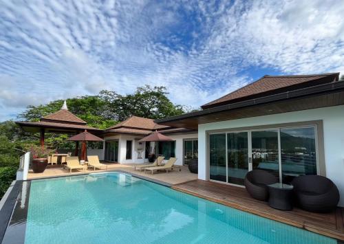 Villa Tantawan Resort - Private Pool Villas في شاطئ كامالا: مسبح وكراسي ومنزل