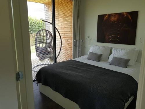 a bedroom with a large bed and a balcony at Sfeervol chalet midden in de natuur in Halle