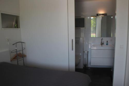 a bedroom with a bed and a sink and a mirror at Sfeervol chalet midden in de natuur in Halle