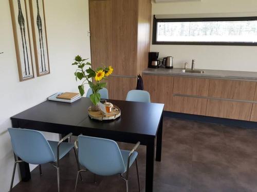 a kitchen with a black table with chairs and a table with flowers at Sfeervol chalet midden in de natuur in Halle