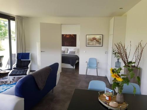 a living room with a blue couch and a bed at Sfeervol chalet midden in de natuur in Halle