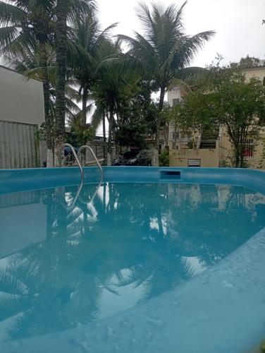una piscina azul con palmeras en el fondo en Suíte Prainha, en Río de Janeiro