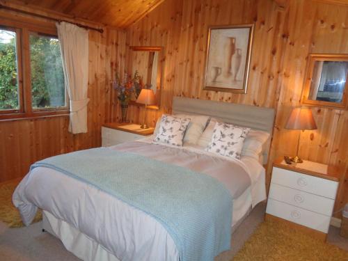a bedroom with a bed and two tables and two lamps at Idyllic Log Cabin Near Stratford upon Avon in Stratford-upon-Avon