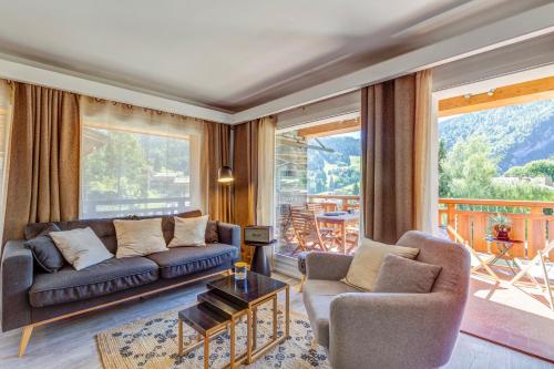 a living room with a couch and chairs and a balcony at Les Chalets de La Clusaz - Appartement le Yeti in La Clusaz