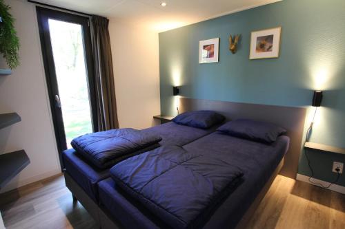 a bedroom with a large bed with blue sheets at Tiny House in Baarle-Nassau