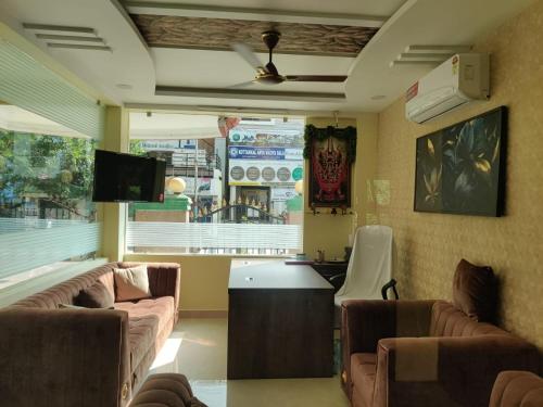 a living room with couches and a tv and a kitchen at JK Home Stay in Tirupati