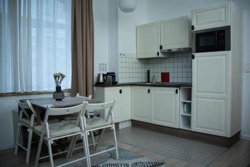 - une cuisine avec des placards blancs, une table et des chaises dans l'établissement House4You - Bălcescu 26, à Bucarest
