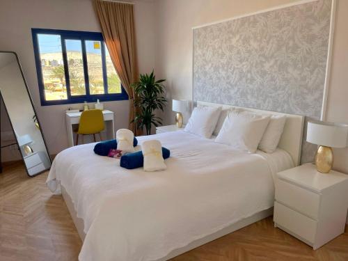 ein Schlafzimmer mit einem großen weißen Bett mit zwei ausgestopften Tieren in der Unterkunft Arilvia good vibes only in Costa Calma