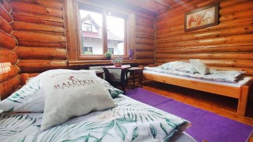 Klimatyczne Domki - Całoroczne في رادومسكو: غرفة نوم بسريرين في كابينة خشب