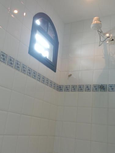 baño con ventana en una pared de azulejos blancos en Suíte Prainha, en Río de Janeiro