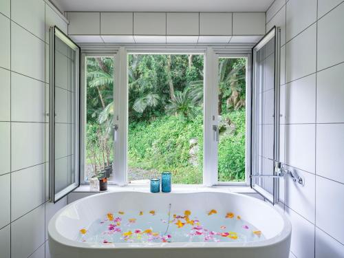 a bath tub in a bathroom with a window at Yama'oto - Nature Luxury Stay in Motobu