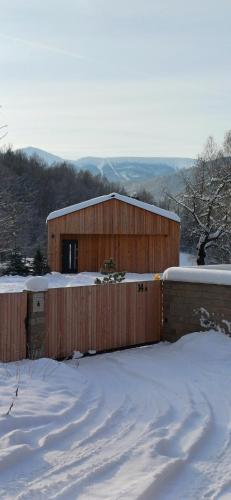 ein Holzgebäude mit einem Zaun im Schnee in der Unterkunft Górnolotnie koło Karpacza in Karpacz