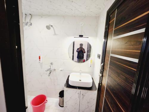 a man taking a picture of a bathroom with a sink at THE GREENSTAR INN PREMIUM in Bhubaneshwar