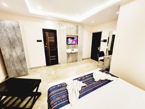 a bedroom with a bed and a chair and a television at THE GREENSTAR INN PREMIUM in Bhubaneshwar