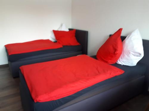 two beds with red and white pillows in a room at Ferienwohnung am Schwimmteich in Lachendorf