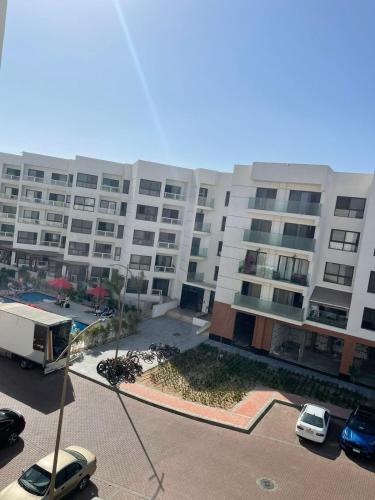 um grande edifício de apartamentos com carros estacionados em frente em Porto said resort em `Ezbet Shalabi el-Rûdi