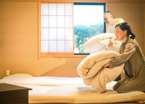 une femme met un bébé sur un lit dans l'établissement 富士の樱House 宝栄, à Fujikawaguchiko
