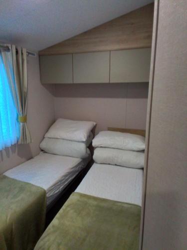 um pequeno quarto com 2 camas e uma janela em 8 Birth Mobile Luxury home C016 8SG St Osyth near Clacton on Sea em Clacton-on-Sea