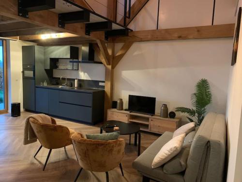 a living room with a couch and chairs and a kitchen at Vakantiehuis Hollestelle in Ovezande