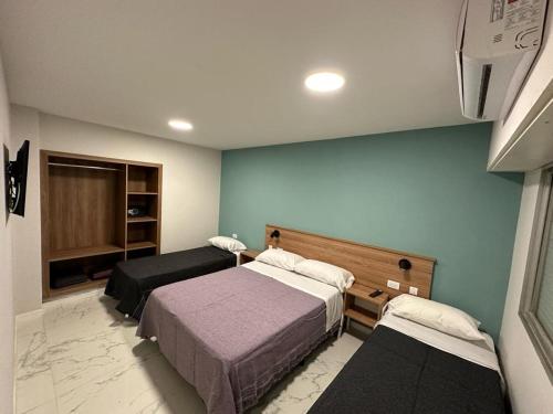 a bedroom with two beds in a room with blue walls at Hotel Bermudas in Mar del Plata