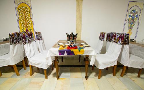 een tafel met stoelen en een tafel met een kat erop bij Hotel Zaringiz in Bukhara