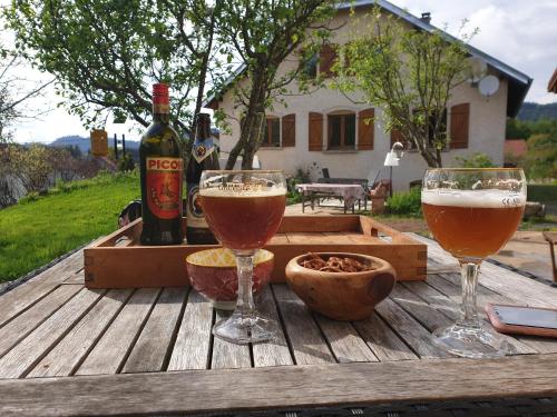 Étival-Clairefontaine的住宿－Nature & bien-être，木桌旁的两杯啤酒和一瓶葡萄酒