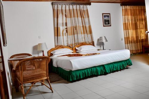 una camera con letto, sedia e tavolo di ROYAL PARK HOTEL AND CHINESE RESTAURANT a Kumasi