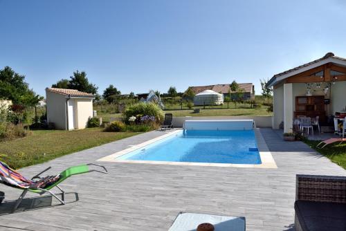 a backyard with a swimming pool and a patio with a chair at Magnifique Studio avec terrasse et accès piscine in Clam