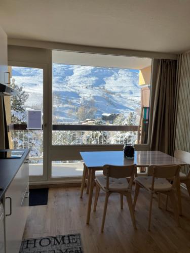 a dining room with a table and a large window at Appartement deux alpes pied des pistes in Les Deux Alpes
