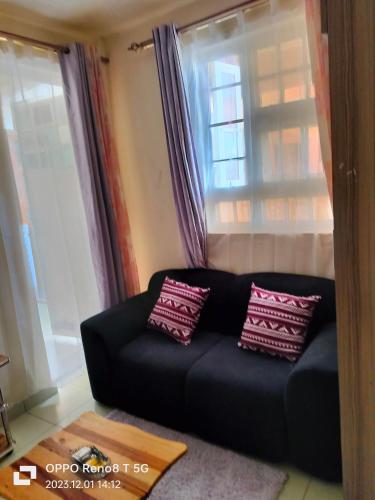 a black couch sitting in front of a window at Gulf breeze heritage in Ruiru