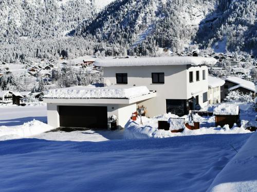 a house covered in snow with mountains in the background at Ferienwohnung Saxenhammer in Vandans