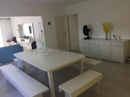 Una cocina con una mesa blanca y bancos en una habitación. en Casa em Tamandaré Próximo ao Mar, en Tamandaré