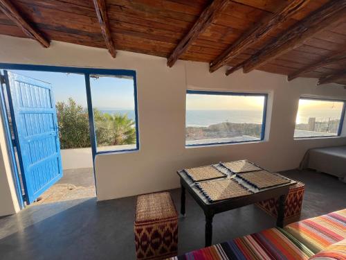 Una habitación con una mesa y vista al mar. en Dar Isma : Une maison sur océan, en Wassane