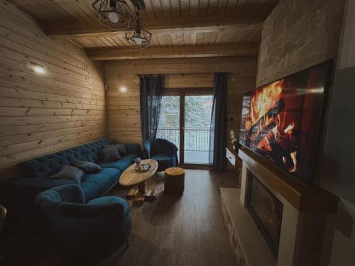 a living room with a blue couch and a tv at Planinska kuća Dunja in Jahorina