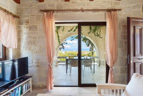 a living room with a large glass door leading to a patio at Villa Calliope St George Retreat BY APOKORONAS-VILLAS in Kókkinon Khoríon