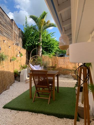 a patio with a table and a chair on a green rug at Gite Ti Bali in Deshaies