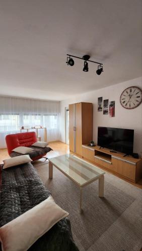 ein Wohnzimmer mit einem Sofa, einem Tisch und einer Uhr in der Unterkunft Apartman Airport in Sarajevo